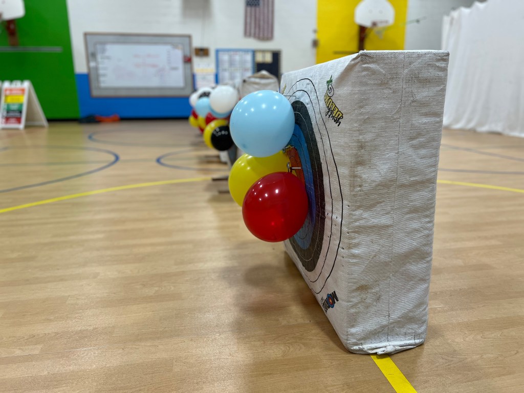 Archery targets with balloons lined up in a gymnasium